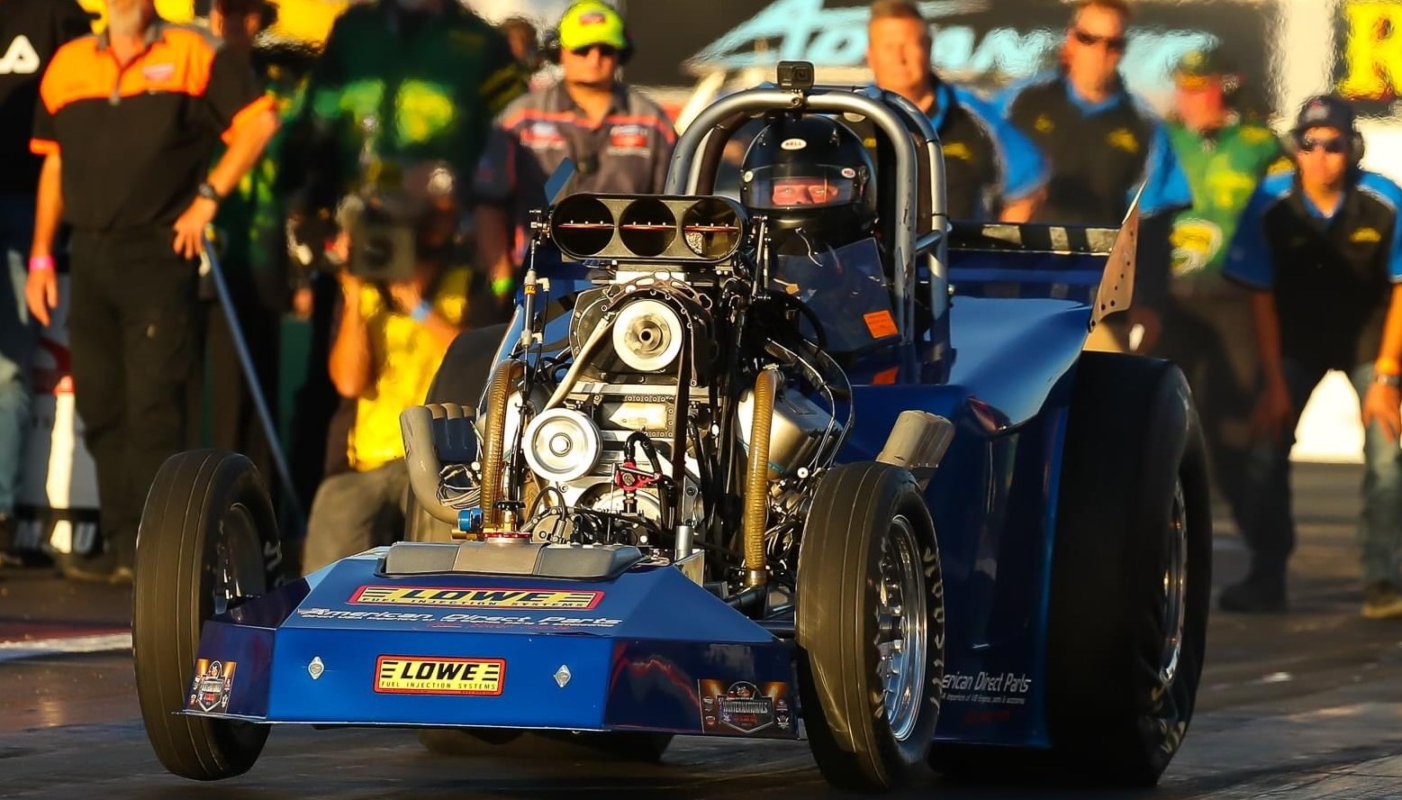 Blue Altered Race Car launching with front wheels suspended in air.